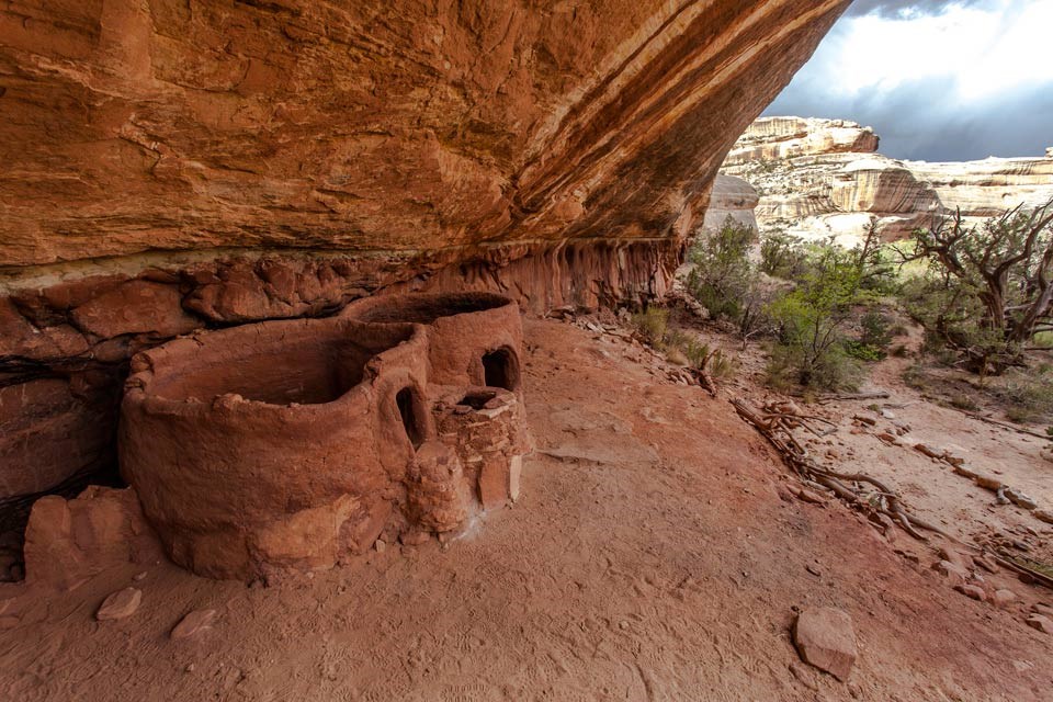 two short, circular structures tucked in an alcove of a canyon