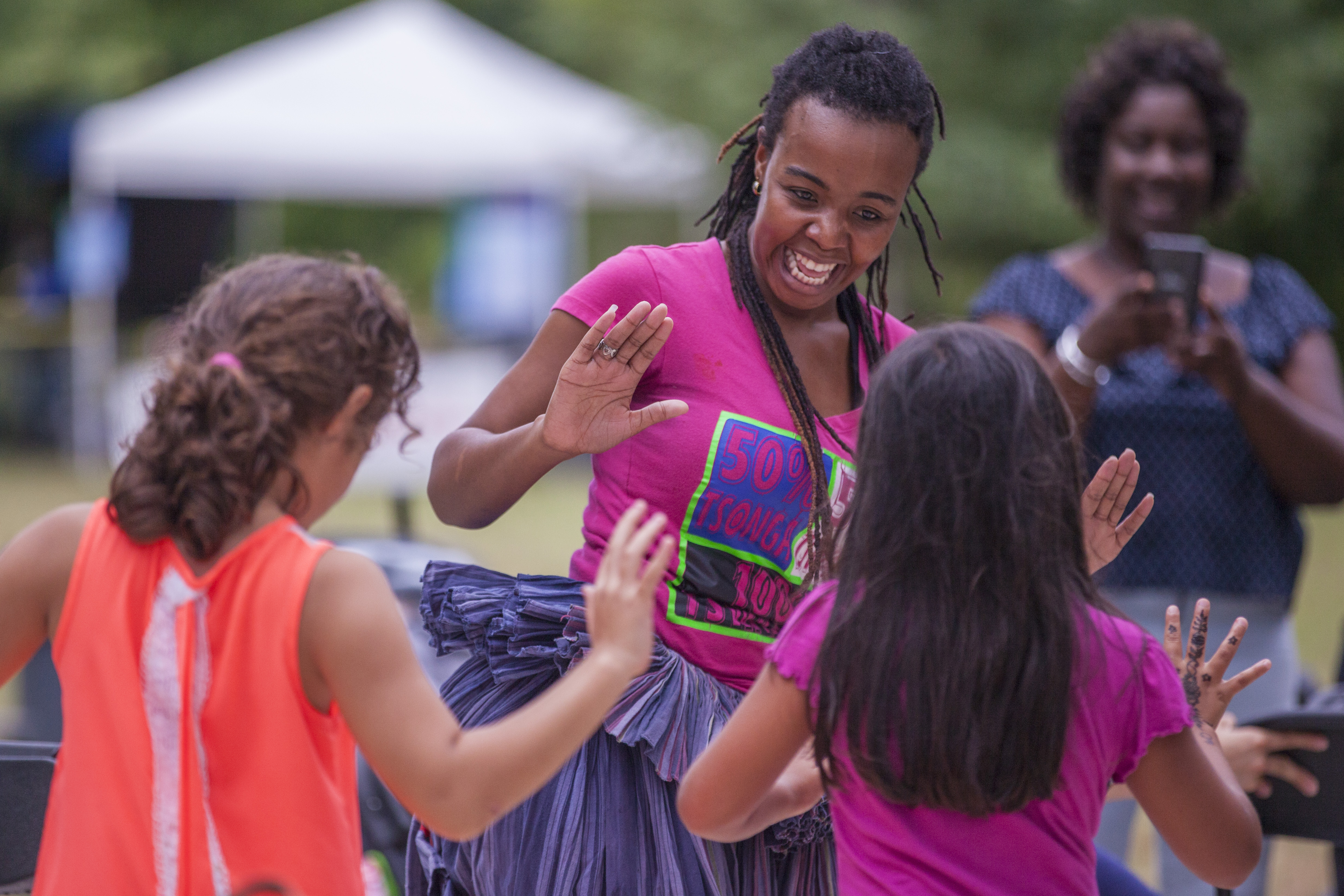 A woman laughs while dancing with two girls