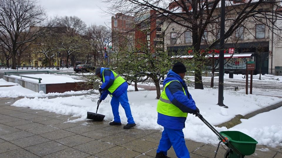 Workers shovel snow from a park
