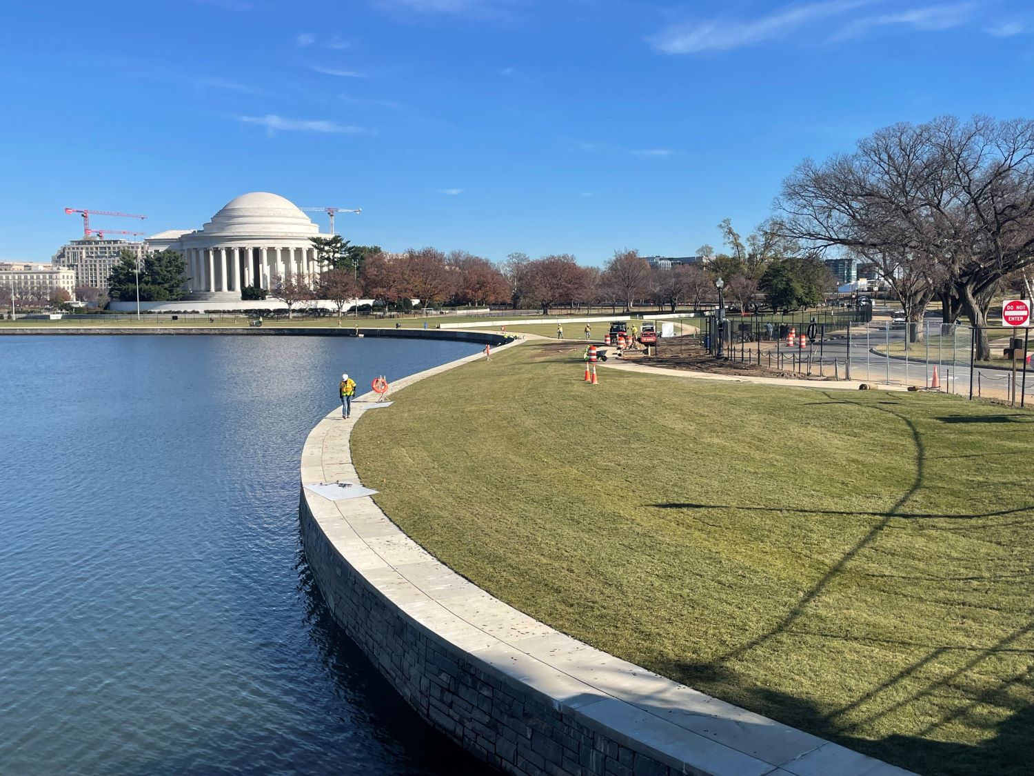 Body of water with walkway on the edge and a white, collonaded building in the background