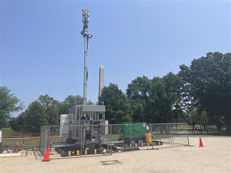 Temporary cellular tower in a field with the Washington Monument in the background