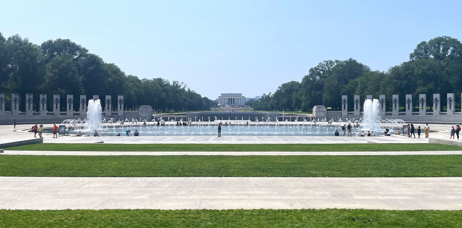 Ornamental fountain among granite columns, with collonaded building in the distance