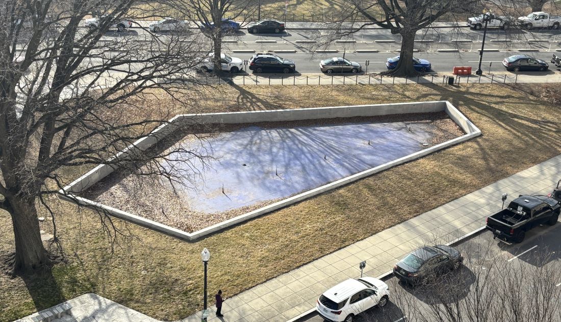 A large, empty pool with leaves accumulating on the bottom