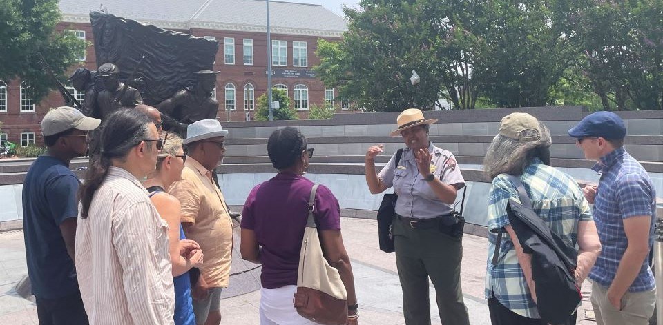 Park Ranger speaks to a group in front of a statue of soldiers