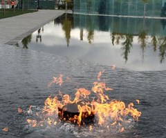 Ceremonial flame rising from the star fountain and reflection of cypress trees