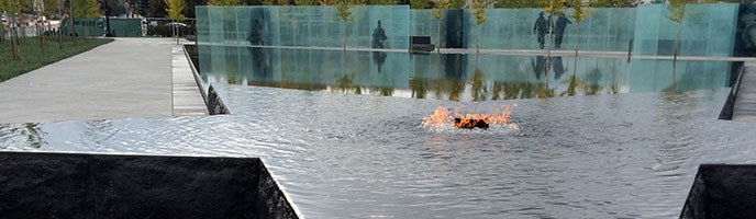 memorial flame in center of star pool, surrounded by glass panels and trees
