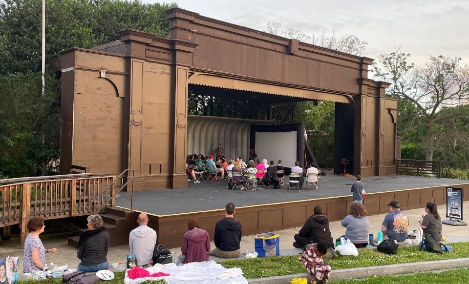A crowd of people watching a program at a covered outdoor stage
