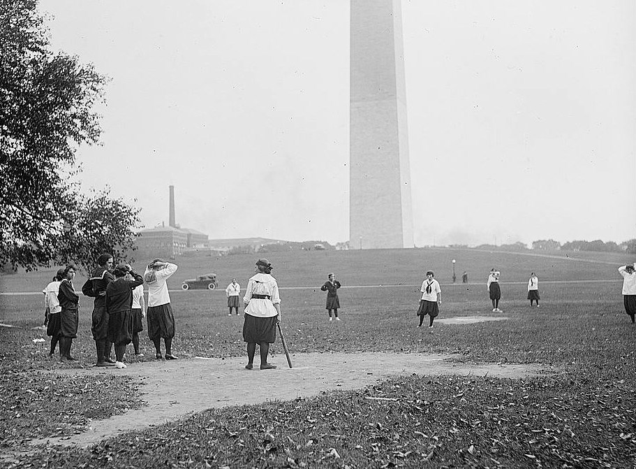 Women playing baseball with the Washington Monument in the background
