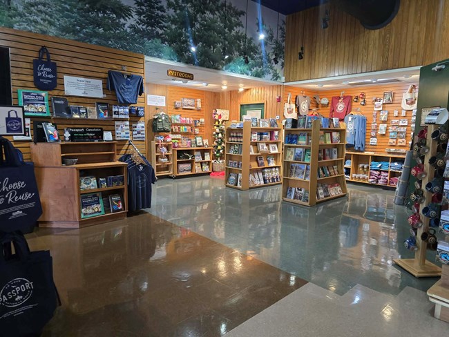 A wide angle of the park store featuring souvenirs like mugs, shirts, hats, books, and postcards.