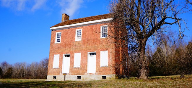 A orange brick two-story historic house and barren tree A orange brick two-story historic house and barren tree