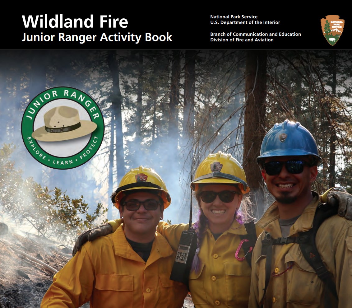 Three people, in yellow shirts and hard hats, in front of smoky trees. The JR Ranger logo and NPS black bar and arrow are across the top.