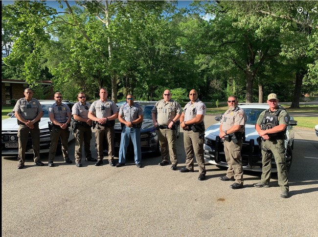 A group of 9 men in law enforcement uniforms, six NPS, three other