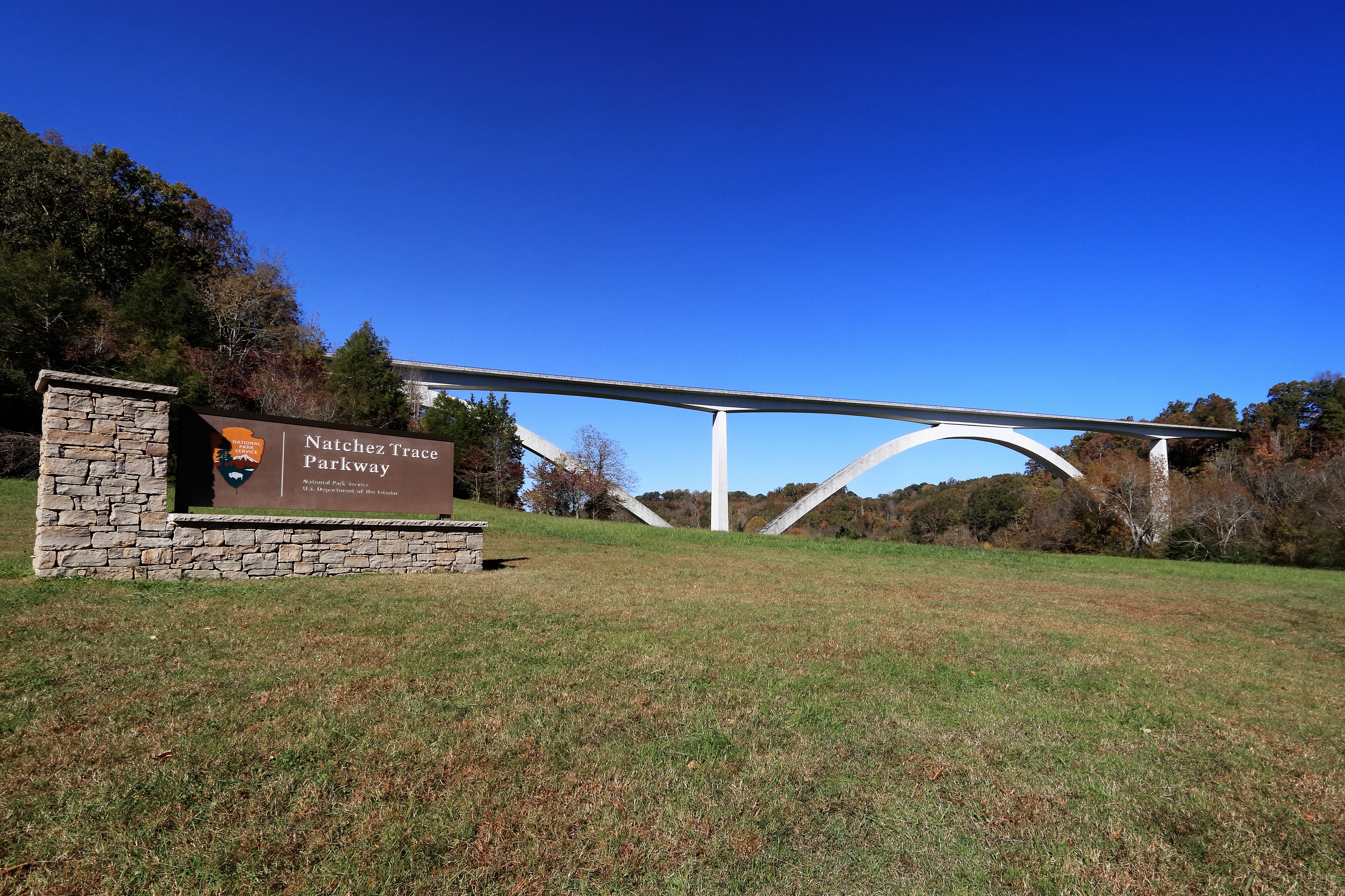 Double Arch Bridge NPS Photo/Bob Boisseau White arched bridge with grass, trees, and national park sign in the foreground.