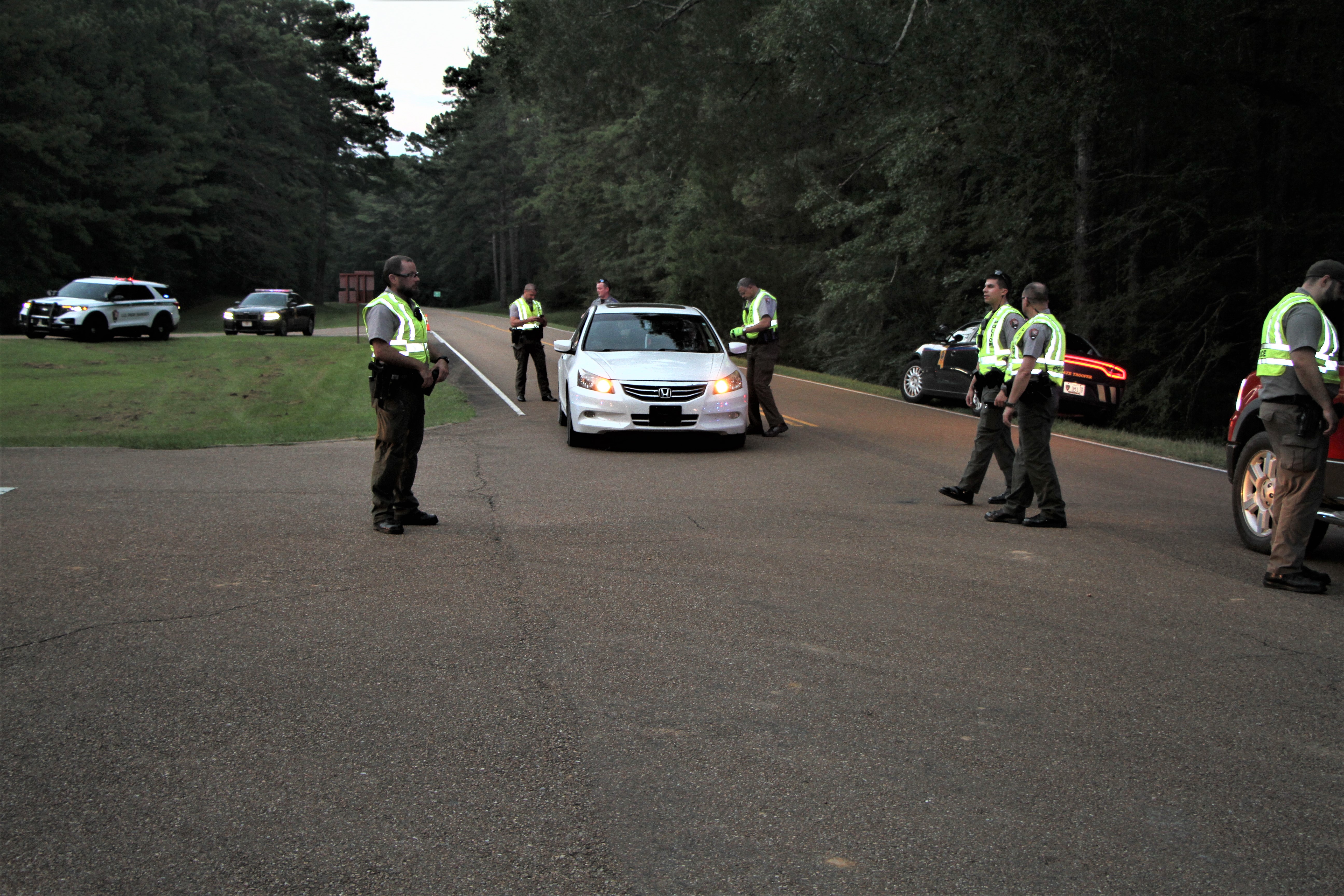 2022 Labor Day Traffic Safety Checkpoint White car is stopped on a tree-lined road where Park Rangers approach for traffic safety checkpoint