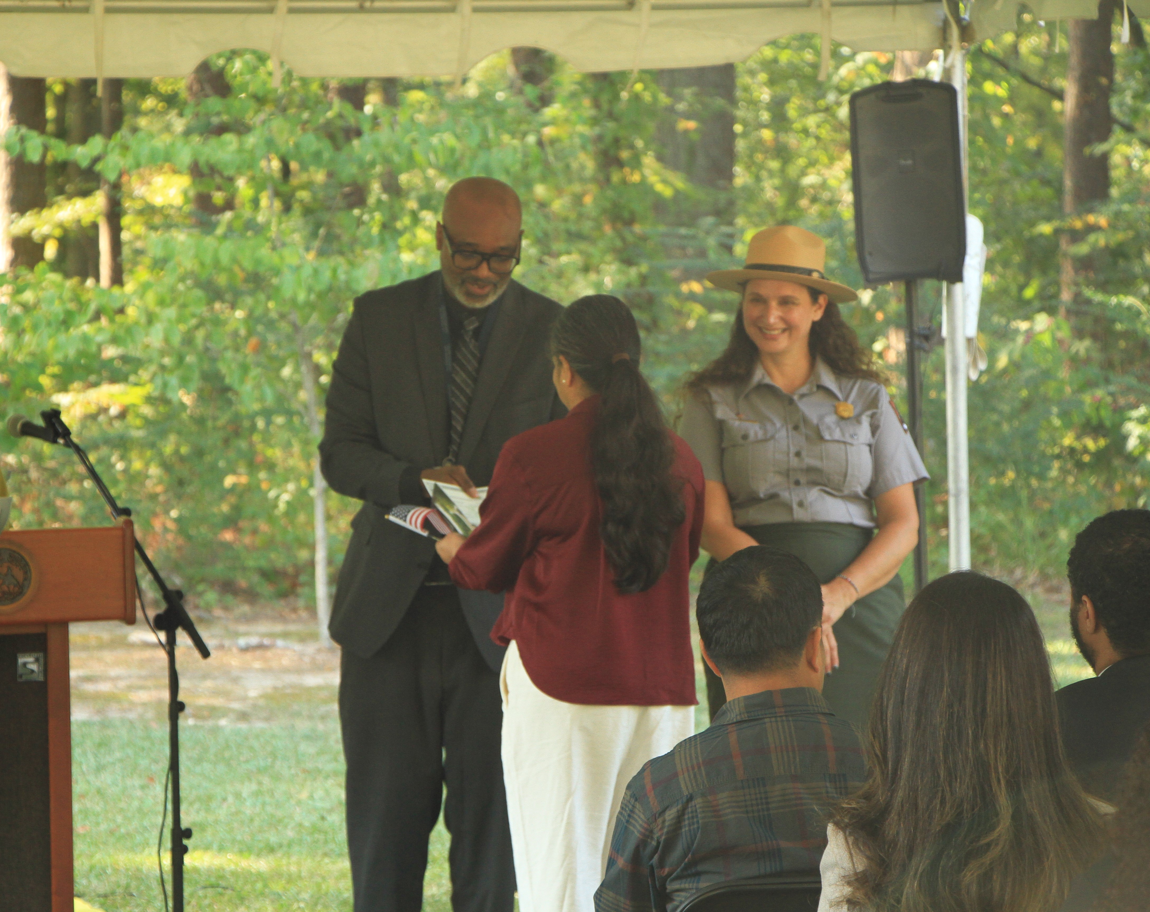 Three people standing together. One person is receiving an award.