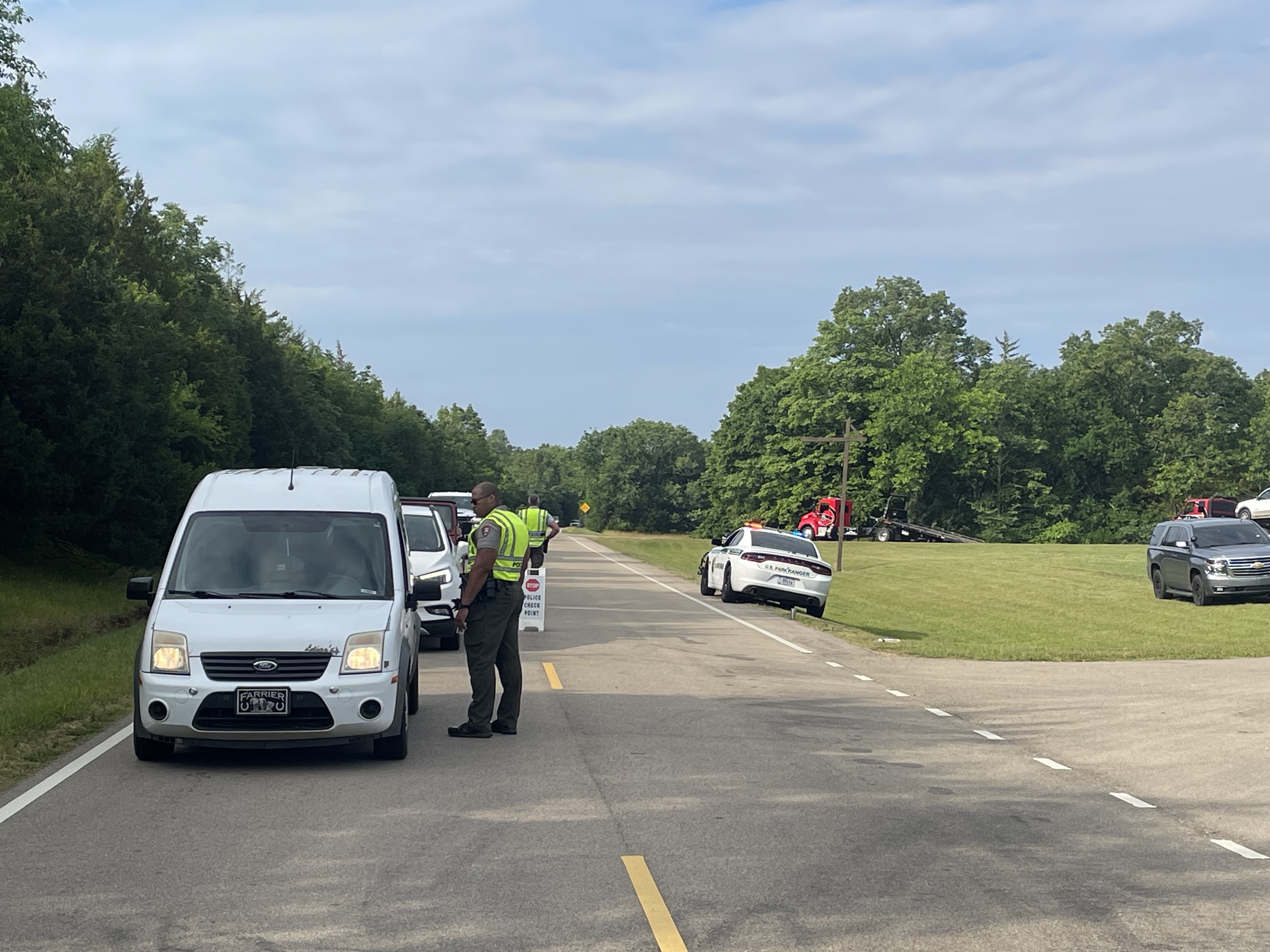 Safety Checkpoint 6 6 2023 Two uniformed rangers talk to drivers in their vehicles a tow truck is in the background.