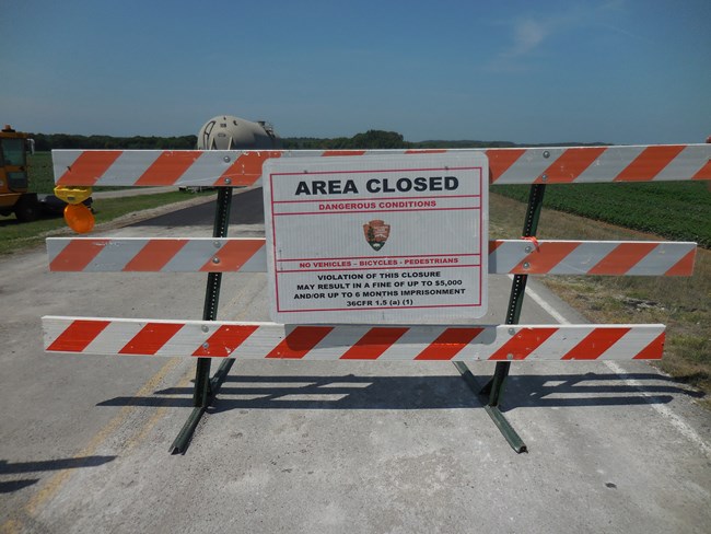 A wooden barrier with a sign that says road closed and fines up to $5000.