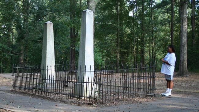 Gravestone surrounded by an iron fence.