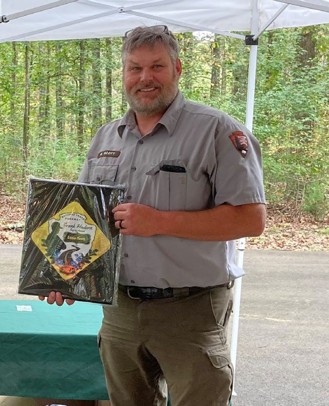 A uniformed man holding an award.