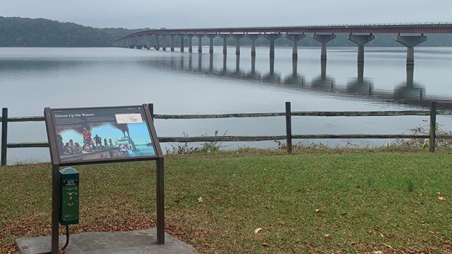 View looking over a large waterway with a bridge across it. There's a sign saying "Trail of Tears Water Route".