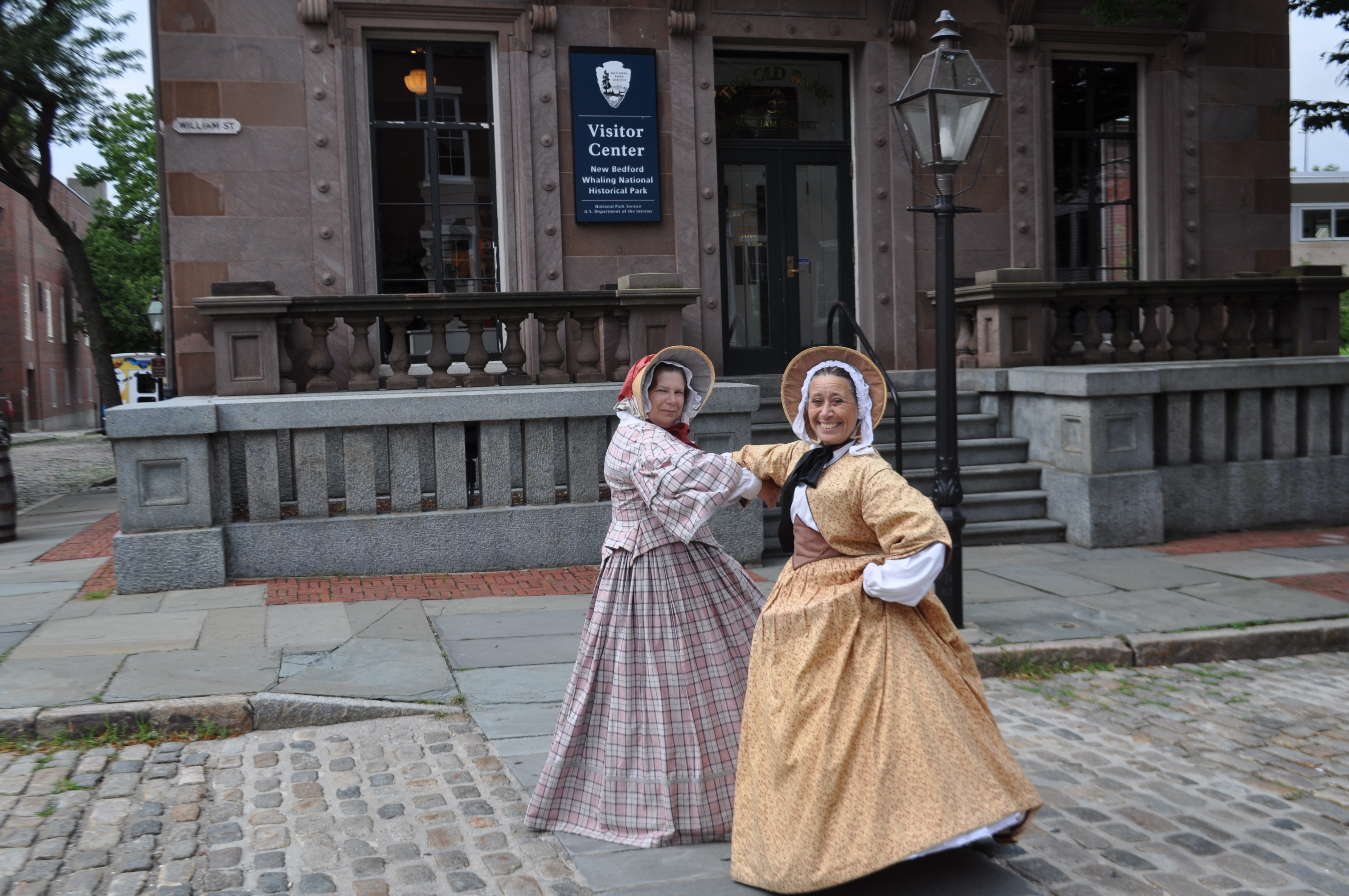 Ruth and Abby dance in the cobblestoned street in front of park visitor center