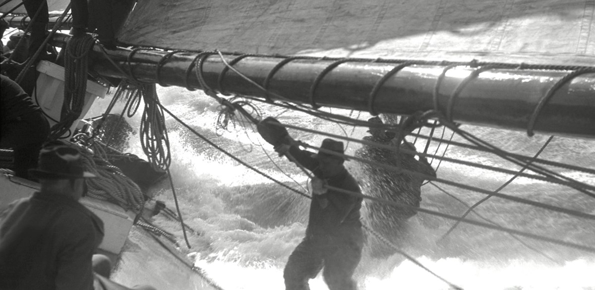 Black-and-white photo: wave comes over the side of the ship.