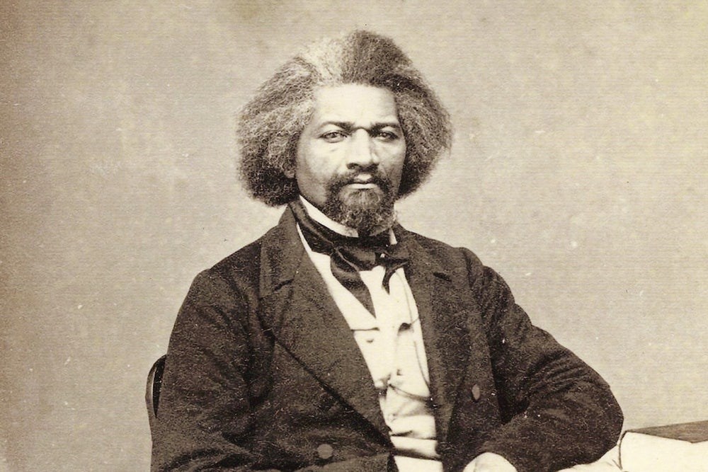Abolitionist Frederick Douglass sits at a table in 1863.