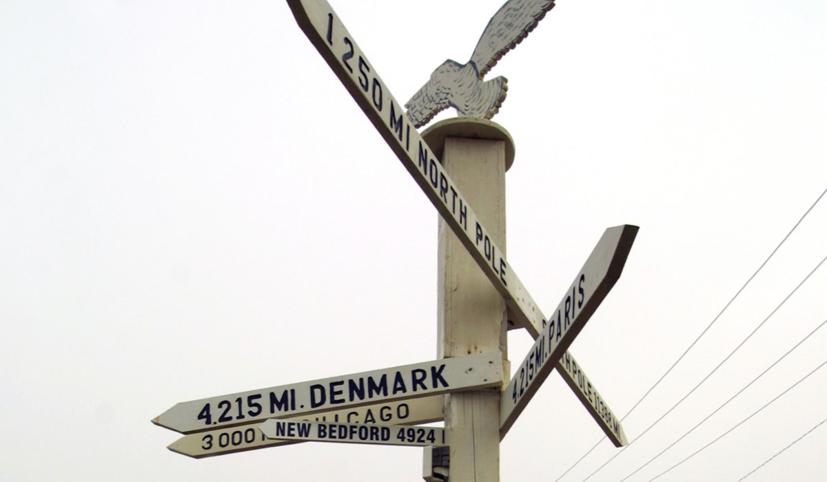 A pole marks the directions for New Bedford, Paris, the North Pole, and Denmark.
