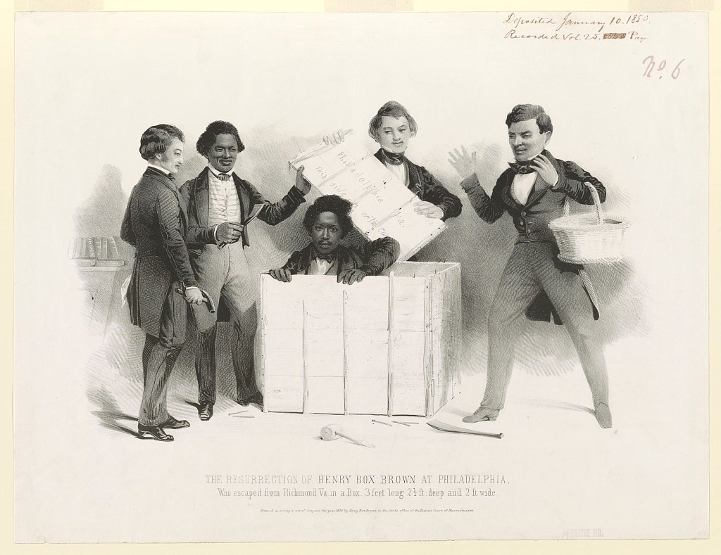 Men help Henry Brown out of a wooden crate.