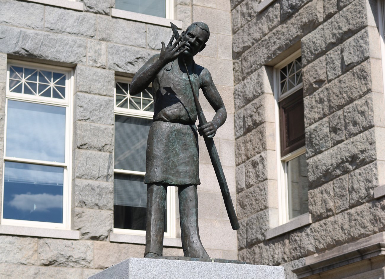 A statue in front of the New Bedford Free Public Library commemorates Lewis Temple. He holds his invention, the toggle iron.