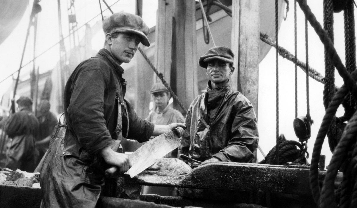 Men work aboard a whaling vessel to cut meat.