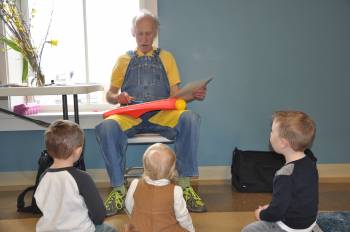 Storyteller plays xylophone with three children watching and listening