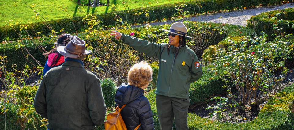 Ranger Jan giving a tour in a lush green garden at the Rotch Jones Duff House