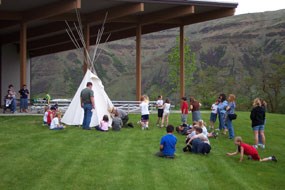 A ranger leading a program of school children around a tipi. A ranger leading a program of school children around a tipi.