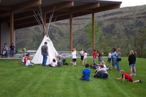 A ranger leading a program of school children around a tipi.