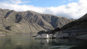 A river surrounded by rocky cliffs and the mountains in the background.