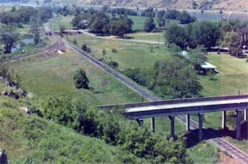 A view from above of railroad tracks going under a bridge.