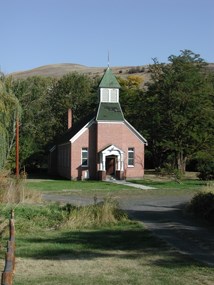 A small Presbyterian church with red brick and a green roof.