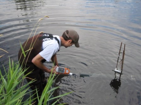 A male aquatic biologist standing in a river monitoring the water quality.