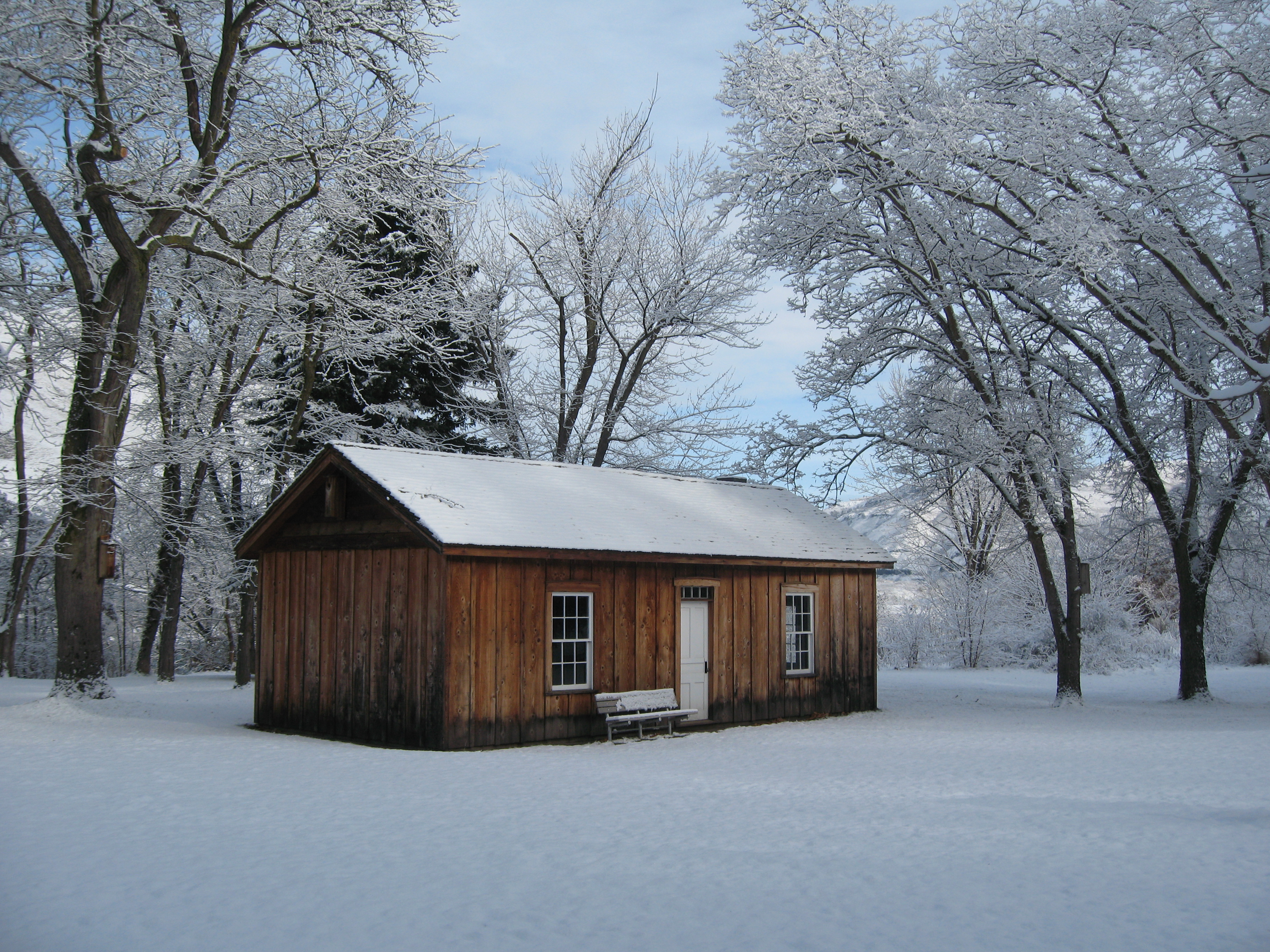 Agency Cabin A wooden cabin sits in a snowy area with many snow-covered trees surrounding.