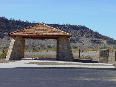 A covered pavilion with a monument next to it on a sunny day.