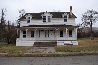 A white two story building with a porch on a cloudy day.