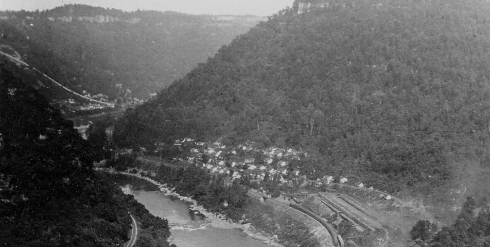 historic photo looking down at a coal town at the bottom of a deep gorge.
