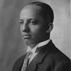 Historic photographic portrait of a young black man in a suit and tie