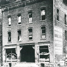 A large three-story brick building with two storefronts on the first floor.