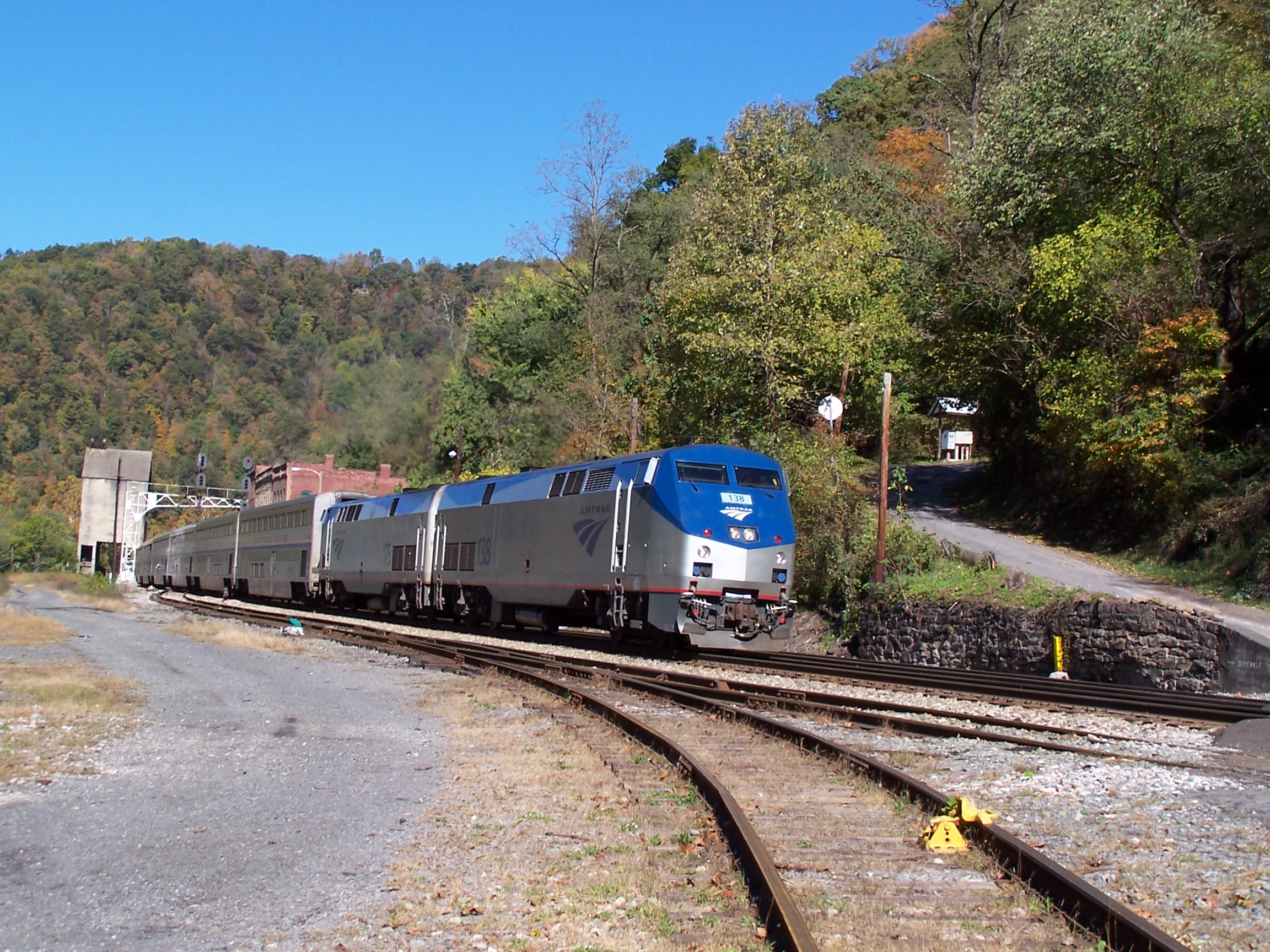 Amtrak locomotive and coaches on rails by historic brick buildings.