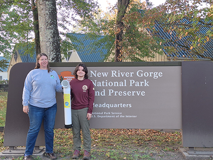 two women standing in front of park sign with fishing line receptacle two women standing in front of park sign with fishing line receptacle