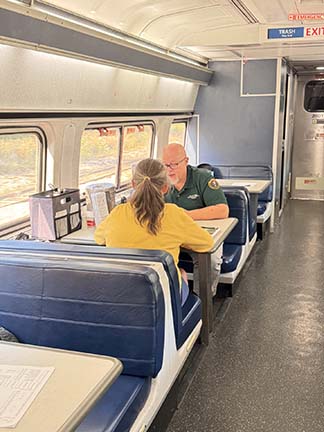 volunteer talks to a passenger in a train car