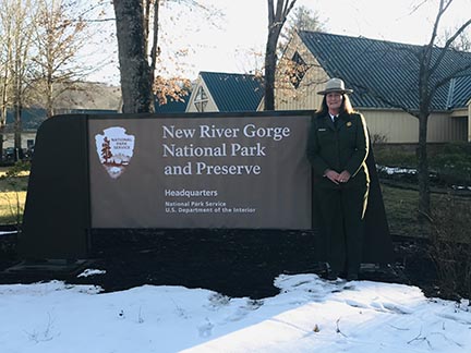 Park ranger in front of park sign