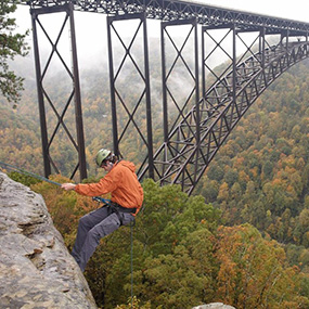 rock climber rappelling next to bridge rock climber rappelling next to bridge